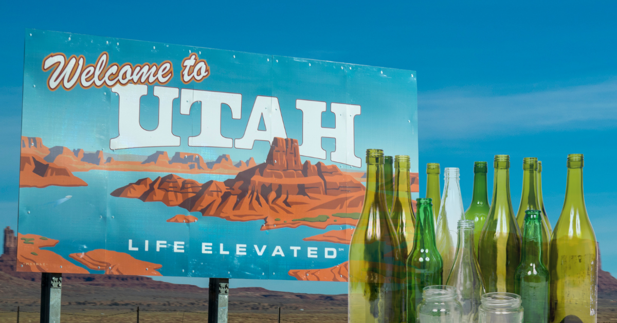 A billboard that says "welcome to utah" appears behind a group of empty bottles