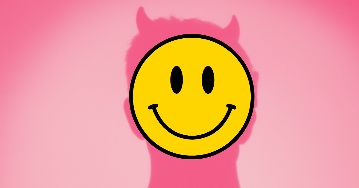 A yellow smiley face appears over the pink shadow of a demon with devil horns.